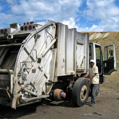 A white garbage truck parked on the side of the road