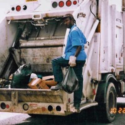 A sanitation worker at the back of a garbage truck