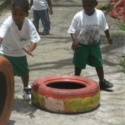 Children in uniform playing with painted tires in the school yard
