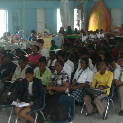 People sitting on chairs listening to addresses at the Goodwill Primary School Exhibition