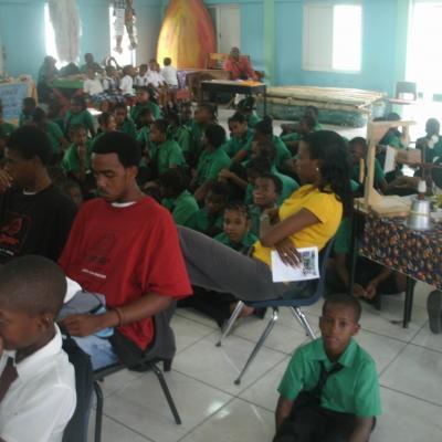 People sitting on chairs listening to addresses at the Goodwill Primary School Exhibition