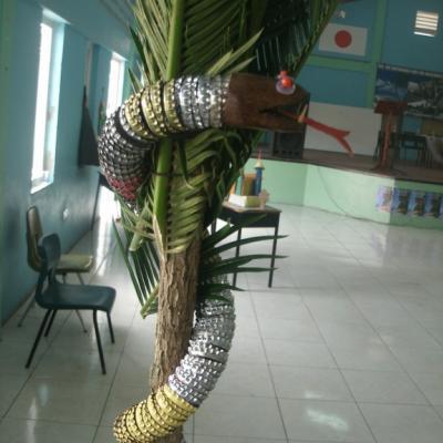 A toy snake made from recycled items wrapped around a palm tree
