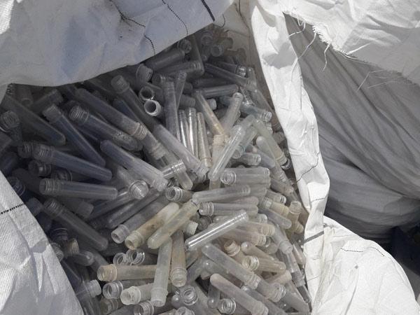A big white bag of plastic test tubles ready for recycling