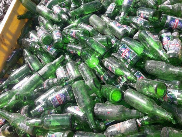 A bin of broken green glass bottles ready for recycling