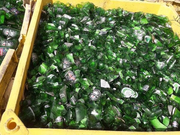 Many bins of broken green glass bottles ready for recycling